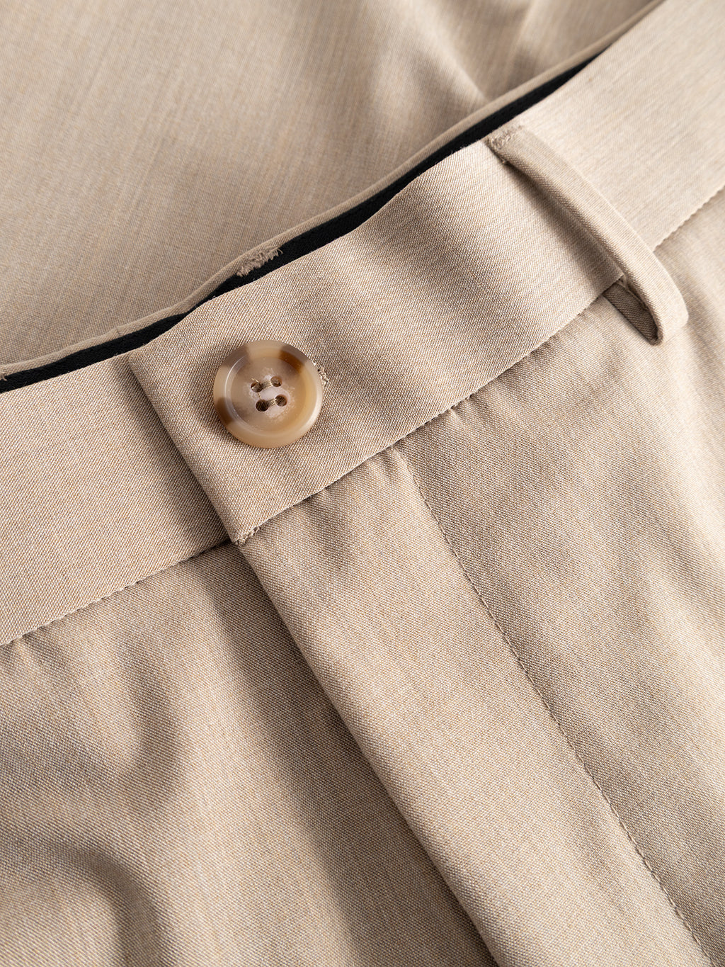 Close-up of the waistband on Gabba GABjoli Tailor Dressy Shorts in Sand, showcasing a brown button, belt loop, and visible stitching detail.