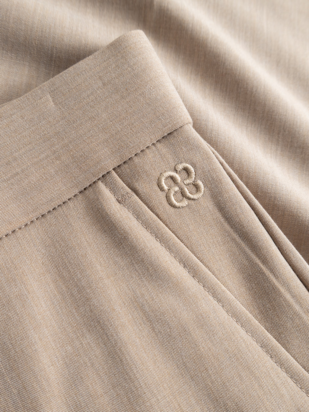 Close-up of Gabba GABjoli Tailor Dressy Shorts in Sand, showcasing a flat waistband, precise stitching, and a subtle embroidered logo by the pocket.