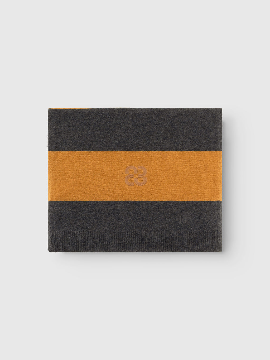 The Gabba GABwest Aico Scarf - Yellow Stripes is a folded merino wool accessory featuring wide horizontal stripes in dark gray and mustard yellow, and a subtle embroidered logo at the center—making it the perfect blend of warmth and style for winter.