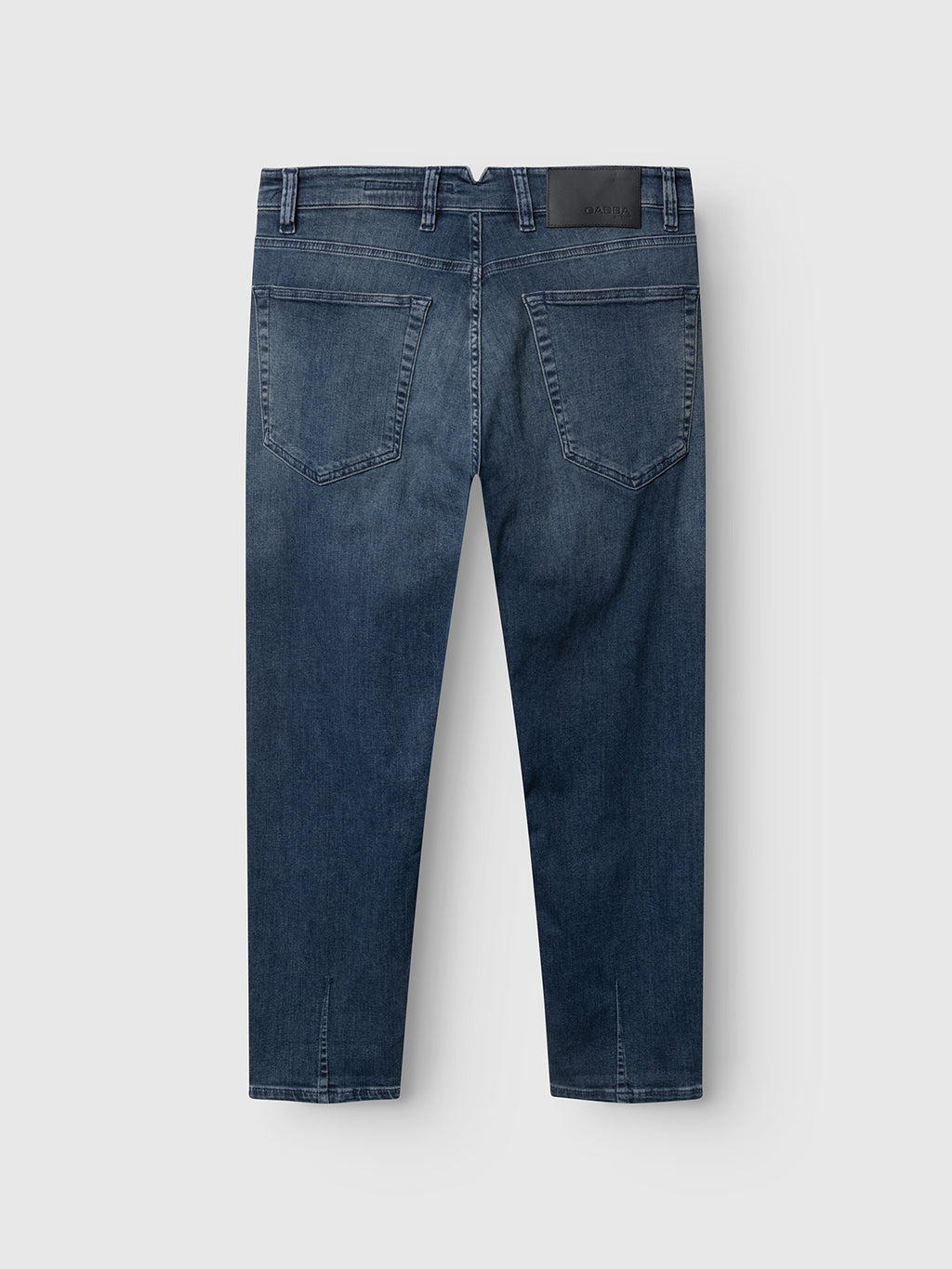 GABalex Cropped Nham RS2113 Jeans by Gabba are shown laid flat on a white background. Made from performance comfort ISKO denim in a dark blue wash, these relaxed tapered fit jeans feature two large back pockets, belt loops, and a black leather patch on the waistband. The jeans are viewed from the back.