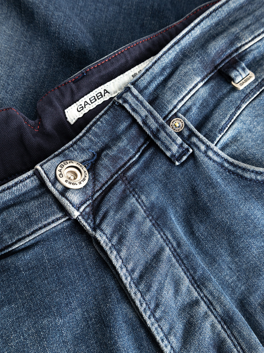 Close-up of GABalex Cropped Nham RS2113 Jeans by Gabba, featuring a visible Gabba label on the waistband, metal button, and belt loops. Crafted from performance comfort ISKO denim in dark blue, these jeans display detailed stitching and texture with a relaxed tapered fit.