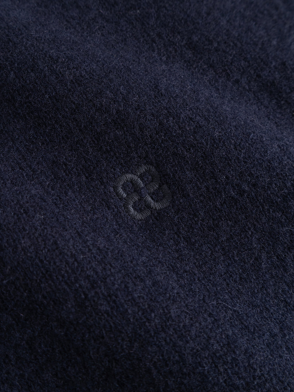 Close-up of the Gabba GABtokota Element Aico LS Knit in navy—a soft, dark blue wool sweater featuring a subtle, small embroidered logo at the center. The fuzzy texture suggests everyday comfort, making this Gabba knit ideal for cooler days.