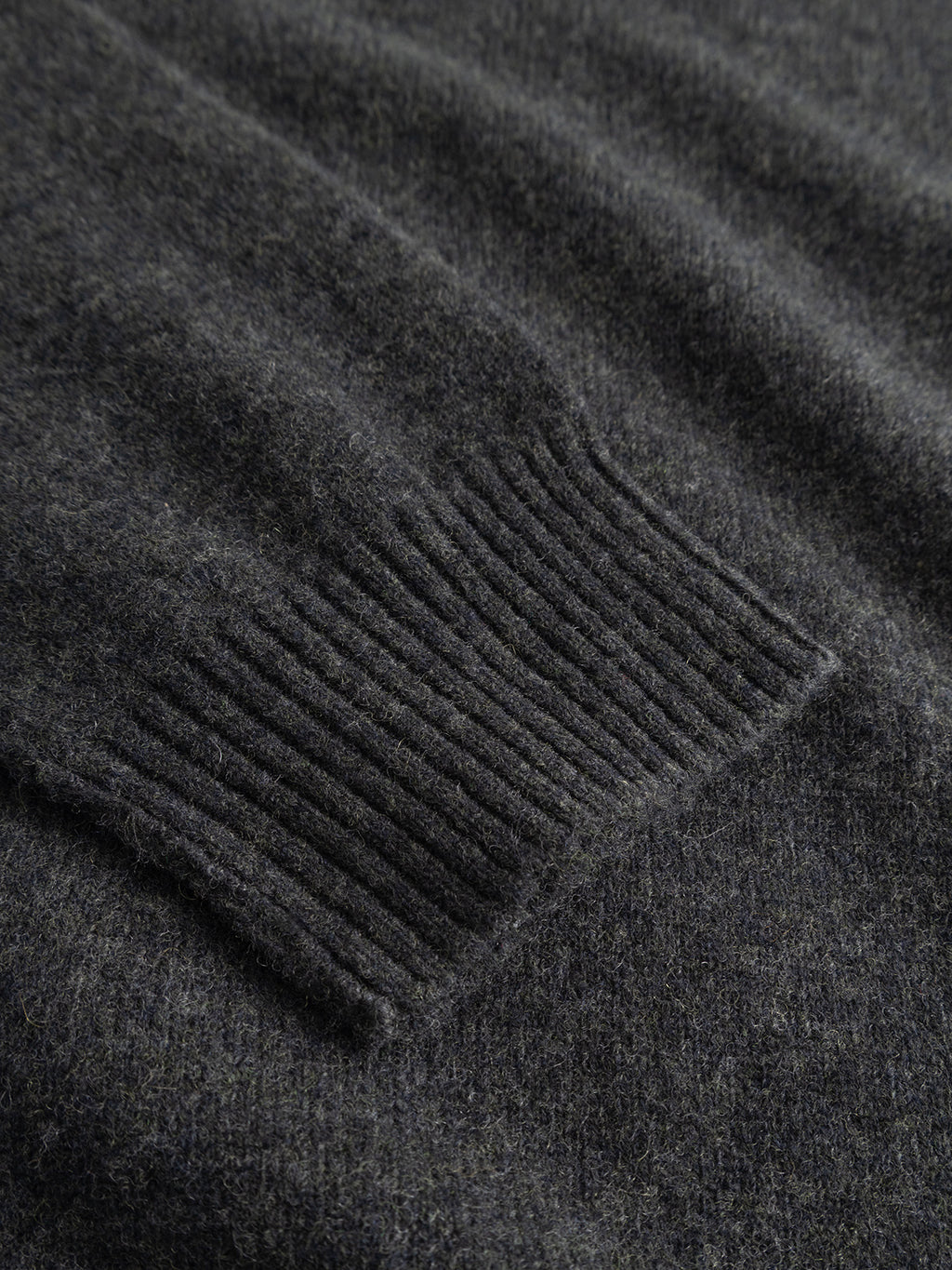 Close-up of a dark grey GABtokota Element Aico LS Knit sweater sleeve by Gabba, featuring a ribbed cuff that showcases the soft, fuzzy texture of the fabric—an inviting detail that highlights the comfort of this wool sweater.