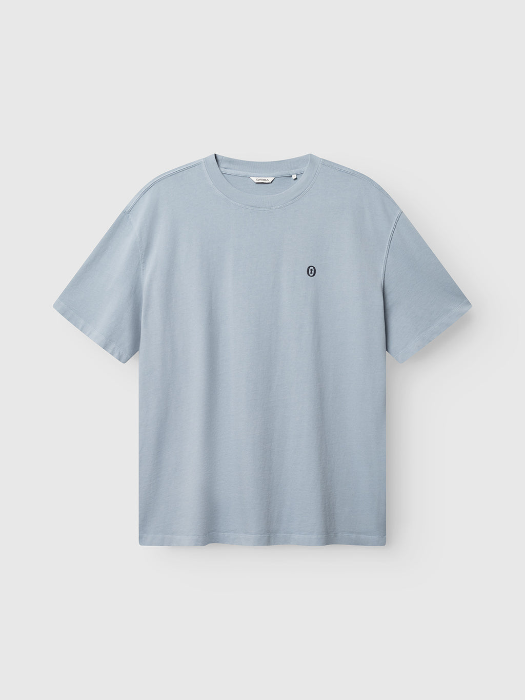 The Gabba GABlegin Wix Boxy Hour Lobby1 SS T-shirt in Dusty Blue features short sleeves, a small black circular logo on the left chest, and is crafted from textured cotton jersey; shown here against a white background.