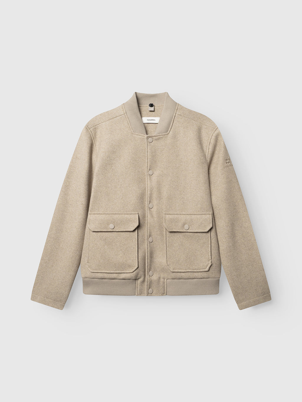 The Gabba GABmatheo Plain Bomber Jacket in Sand features a wool-inspired beige fabric, two spacious front flap pockets, ribbed cuffs and hem, and a snap button closure. Displayed against a plain white background, this versatile piece is an excellent choice for casual outerwear.