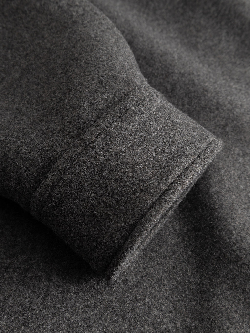 Close-up of the GABtheo City Jacket by Gabba in dark grey, highlighting the soft, textured wool-inspired fabric and the neatly finished sleeve hem—ideal for effortless everyday layering.