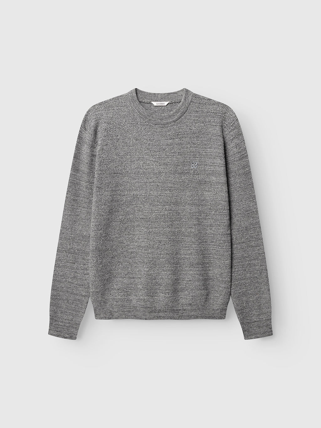 A light grey GABlamix Coro O-Neck LS Knit sweater by Gabba, crafted from a cotton-blend with long sleeves and a crew neckline, is displayed against a plain light background. The sweater features a subtle textured pattern and a small embroidered logo on the left chest.
