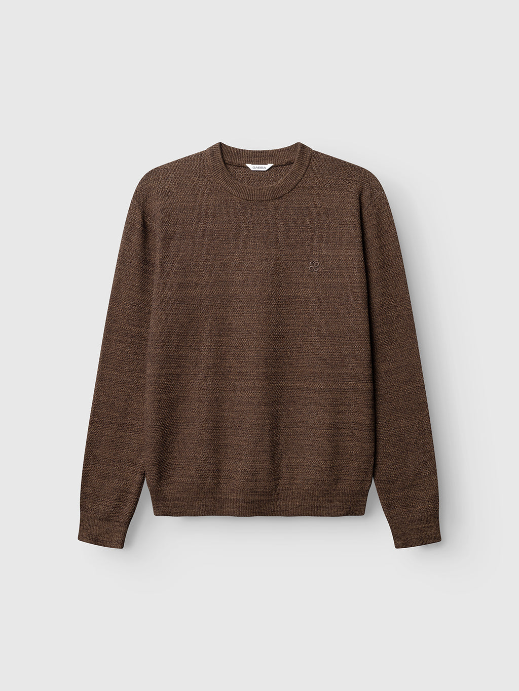 The GABlamix Coro O-Neck LS Knit in Brown Slate by Gabba is a cotton-blend crewneck sweater with long sleeves, shown against a plain light gray background. This minimal and comfortable regular-fit knit features a subtle textured finish and a discreet small chest logo, offering effortless style.