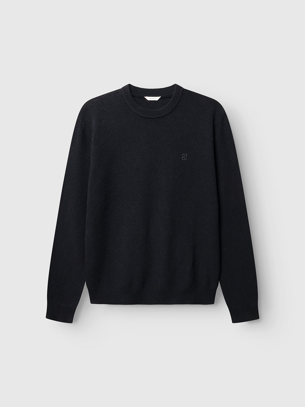 The Gabba GABlamix Coro O-Neck LS Knit in Blue Black is a regular fit, cotton-blend crew neck sweater with long sleeves, displayed against a light gray background. It features ribbed cuffs, neckline, and hem, along with a subtle embroidered logo on the left chest.