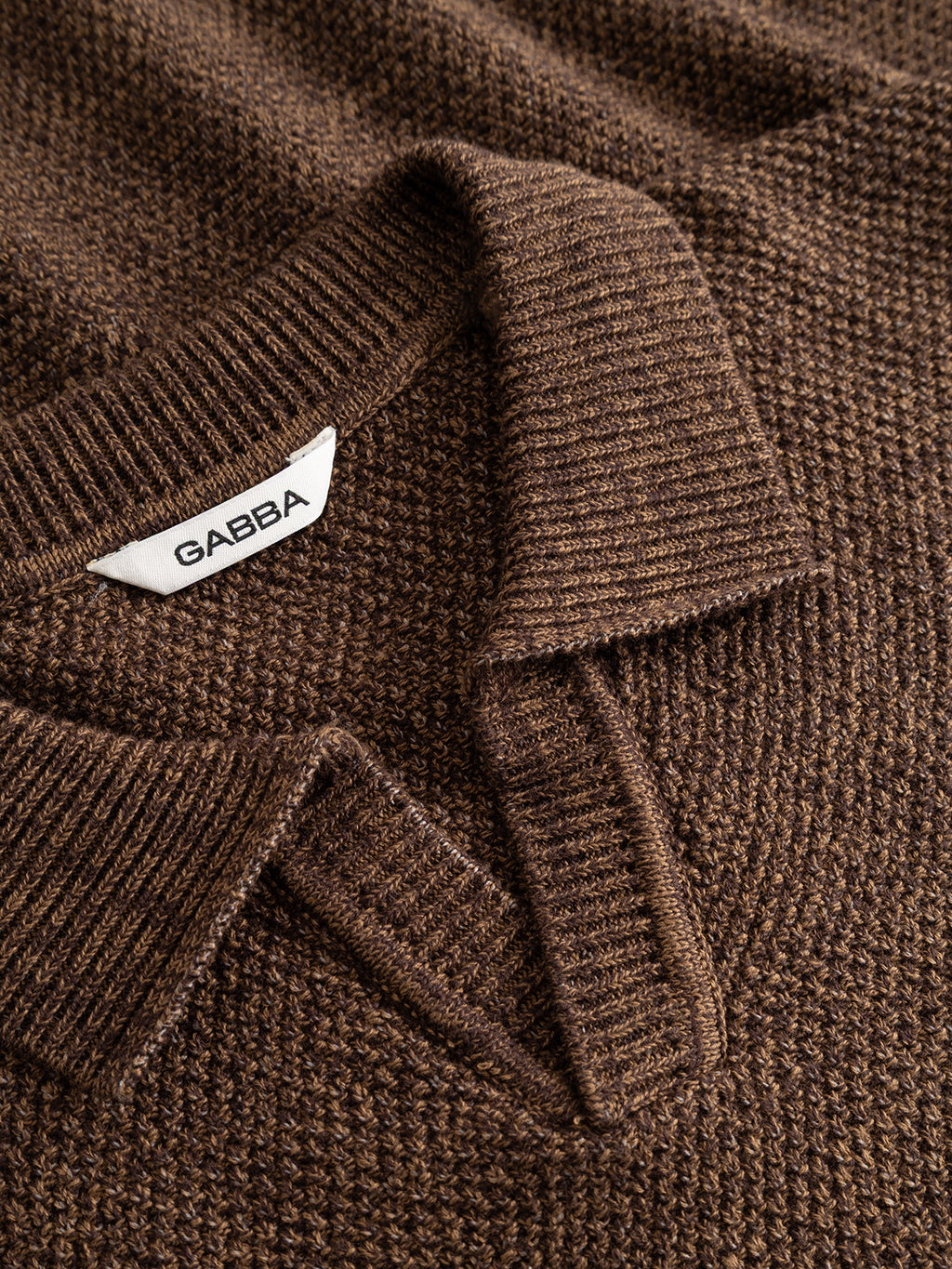 Close-up of the GABlamix Coro Jhon LS Knit in Brown Slate, a textured cotton-blend sweater by Gabba, featuring a ribbed polo collar and a white tag with the Gabba brand mark.