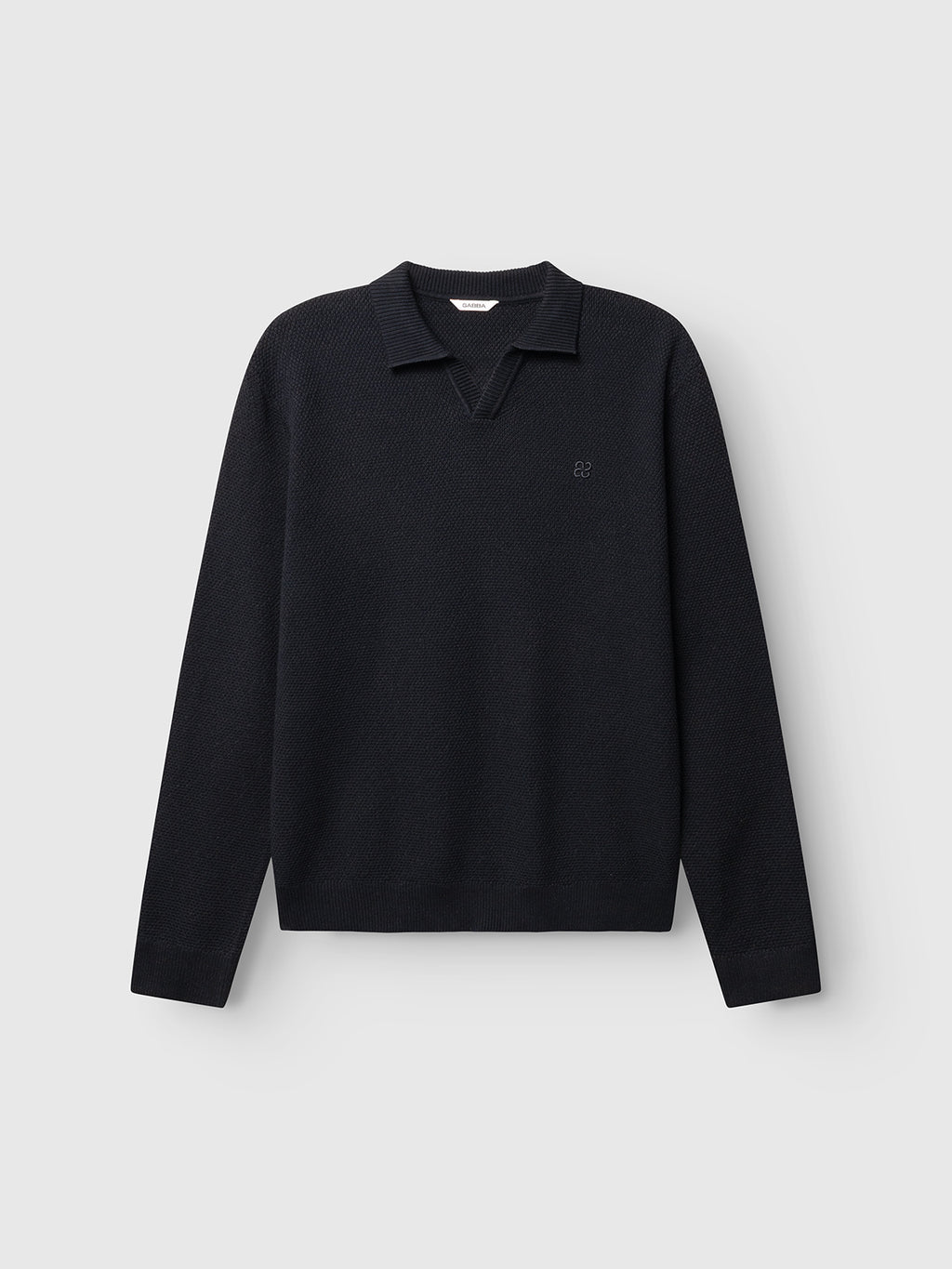 The GABlamix Coro Jhon LS Knit by Gabba is a blue-black long-sleeve cotton-blend sweater featuring a ribbed polo collar and a small embroidered logo on the left chest, showcased against a plain light gray background.