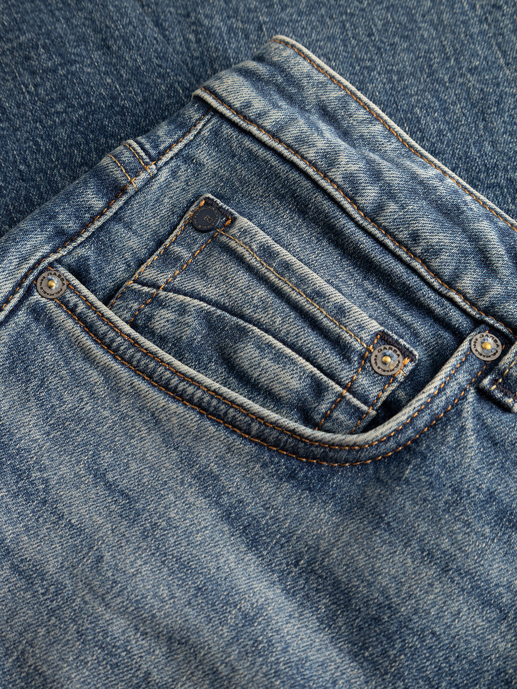 Close-up of the Gabba GABmarc Silvi DS0007 Jeans in Mid Blue Denim, highlighting the comfort stretch fabric, front pocket, small coin pocket, and visible stitching details against a denim backdrop.