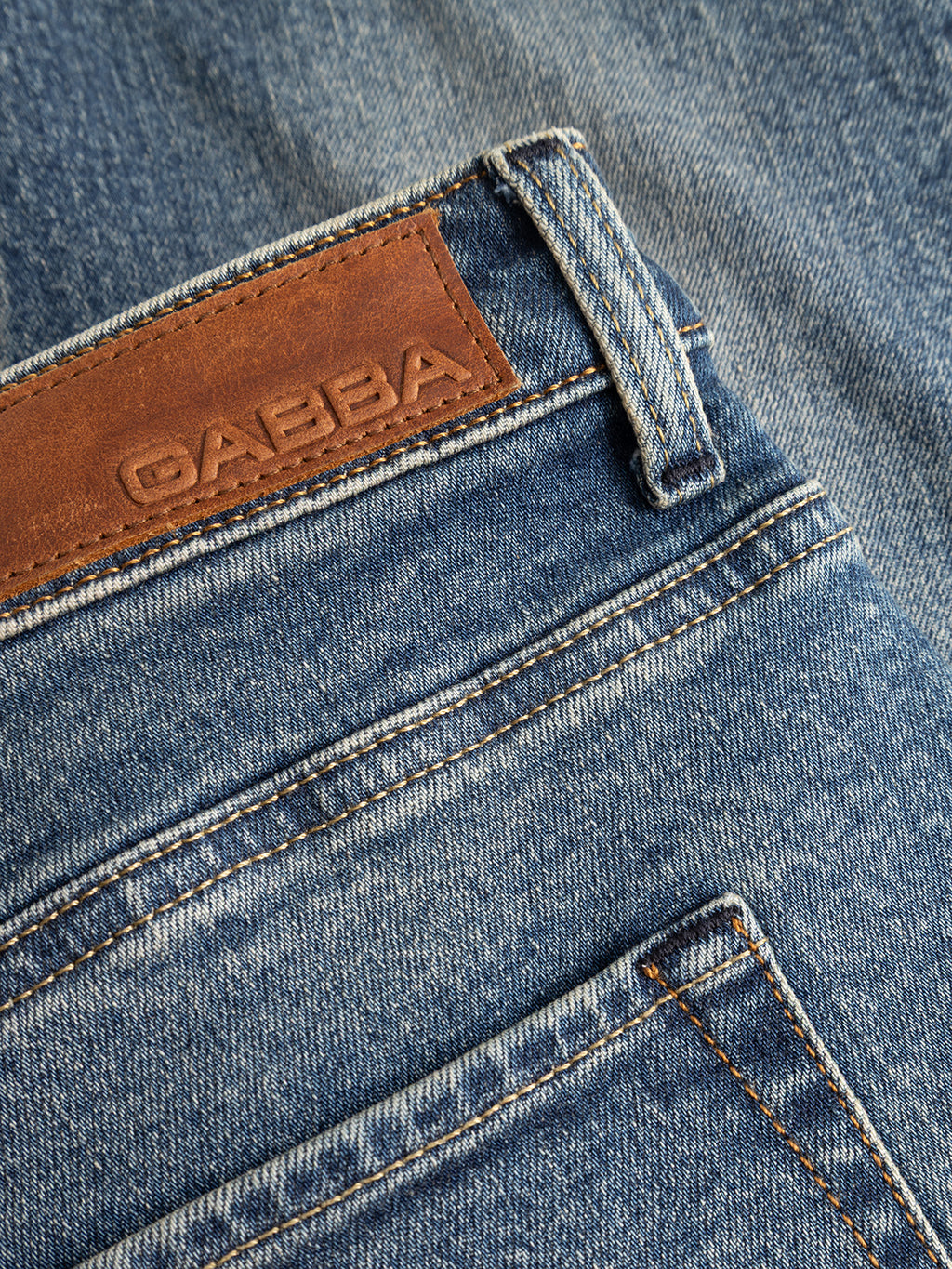 Close-up of the Gabba GABmarc Silvi DS0007 Jeans in mid blue denim, showcasing comfort stretch fabric, a brown leather patch with embossed branding, and visible stitching near the back pocket.