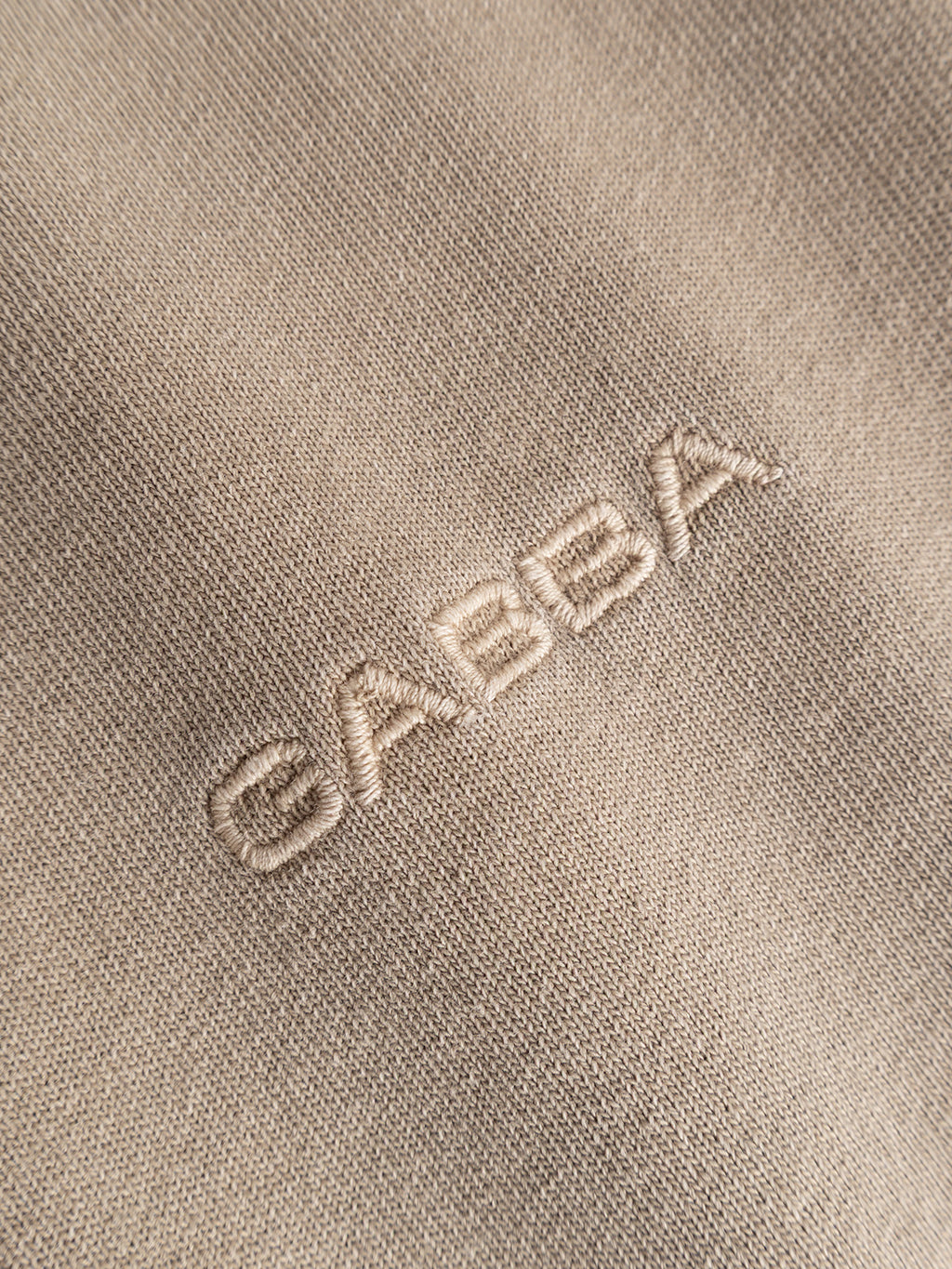 Close-up of the GABlegin Wix Boxy Hour SS T-shirt in Sand Crocker by Gabba, showcasing its beige mid-weight cotton jersey fabric with a white embroidered Gabba logo. The texture and stitching are clearly visible, emphasizing the t-shirt’s relaxed boxy fit.