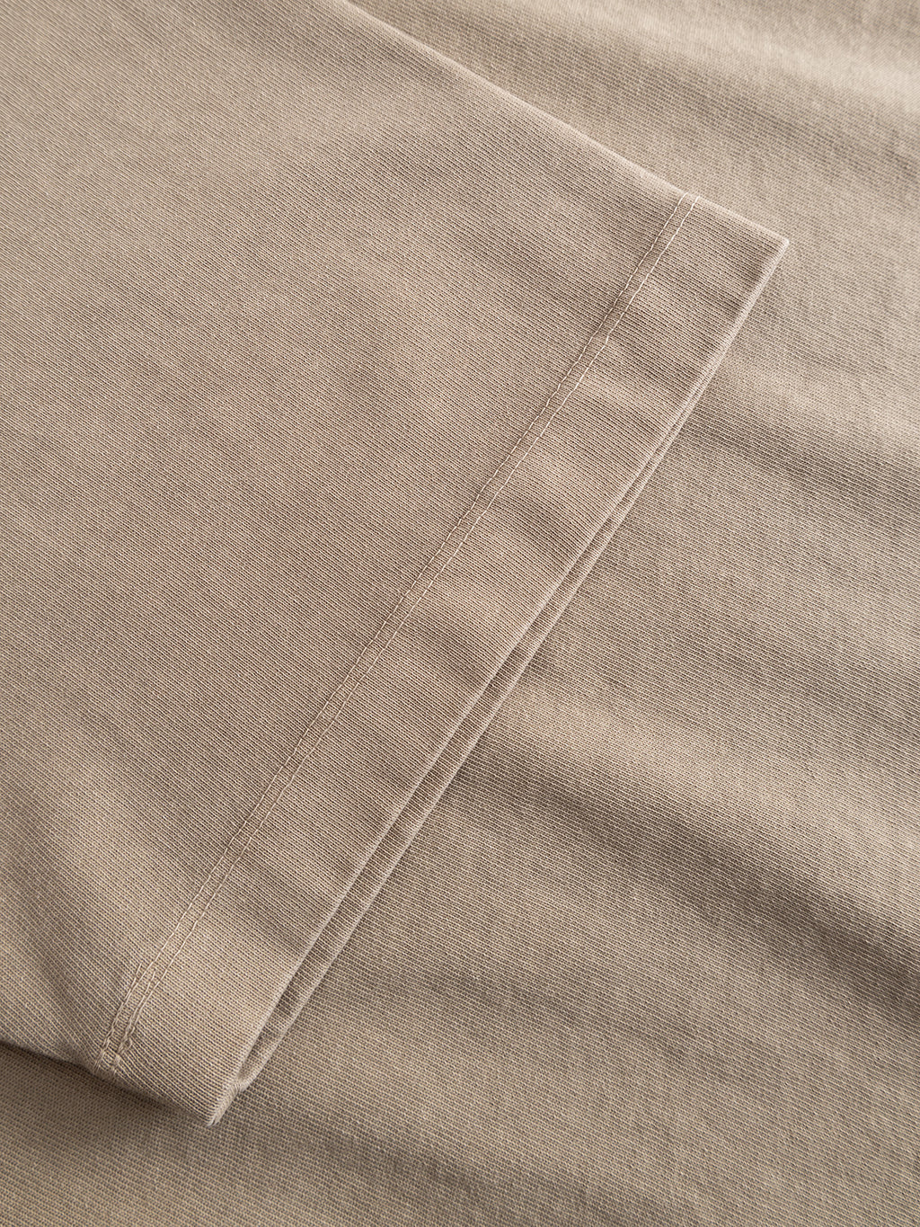 Close-up of the Gabba GABlegin Wix Boxy Hour SS T-shirt in Sand Crocker, featuring beige mid-weight cotton jersey fabric with detailed hem and sleeve stitching, laid flat on a matching background.