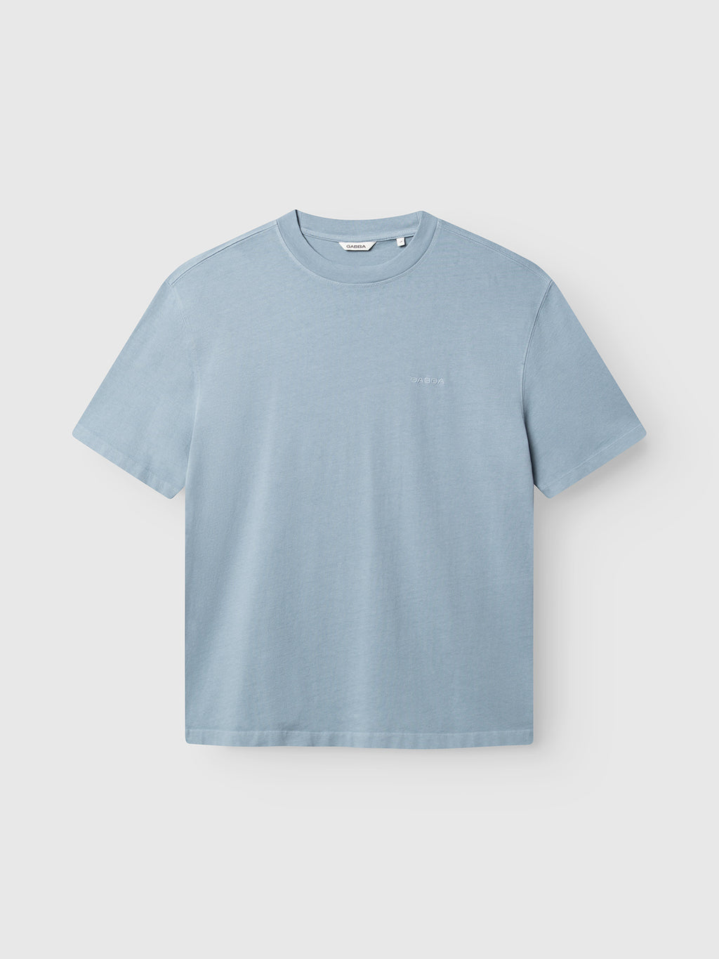 The Gabba GABlegin Wix Boxy Hour SS T-shirt in Dusty Blue is shown on a plain white background. Made from soft, garment-washed cotton, this short-sleeve t-shirt features a relaxed boxy fit and classic crew neckline. The minimalist design is complemented by an understated embroidered Gabba logo for a subtle finishing touch.