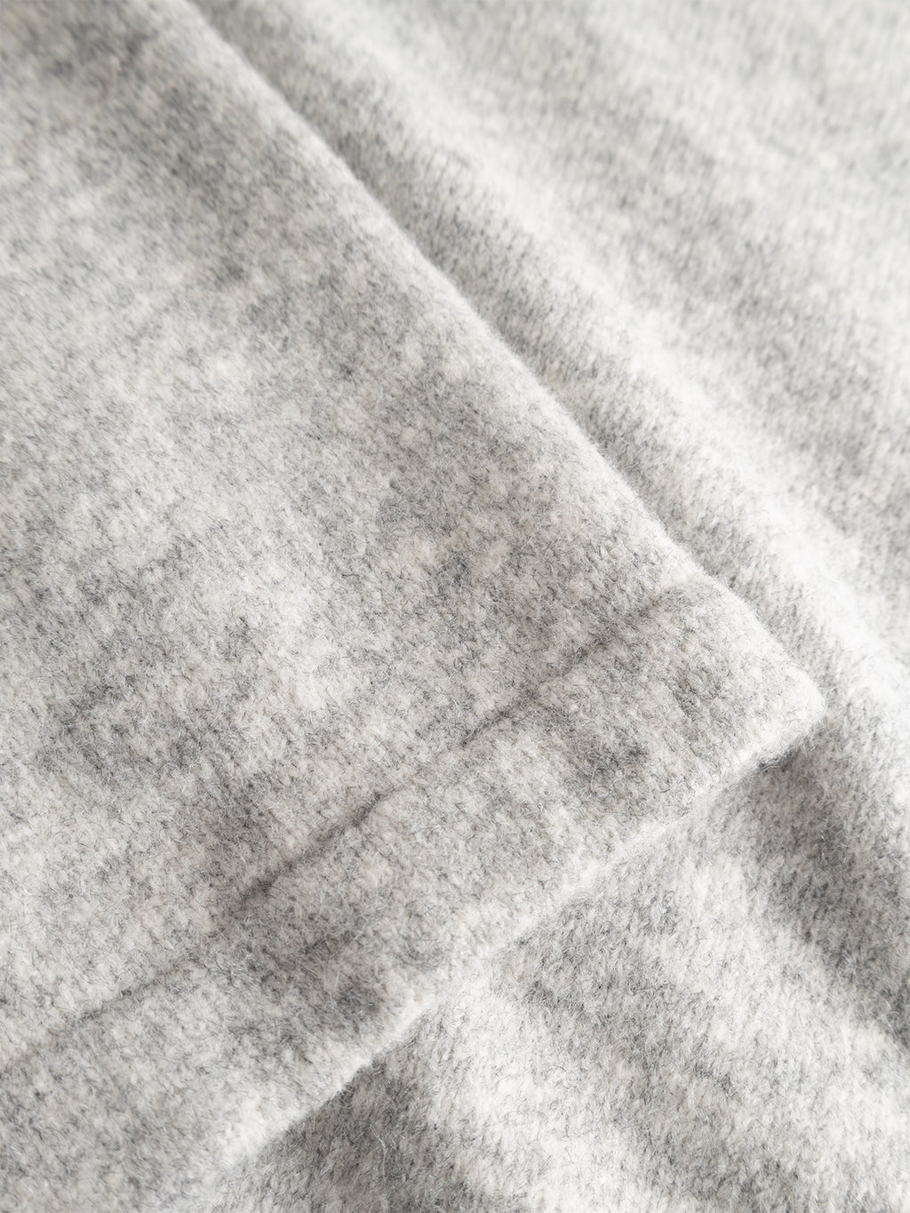 A close-up view of the Gabba GABpietro Polo Argyle LS Knit in Light Grey Mel, featuring soft, light gray fabric with a subtle heathered texture and a folded edge running diagonally across the image, capturing the luxurious cotton blend and modern design of this premium polo knit.