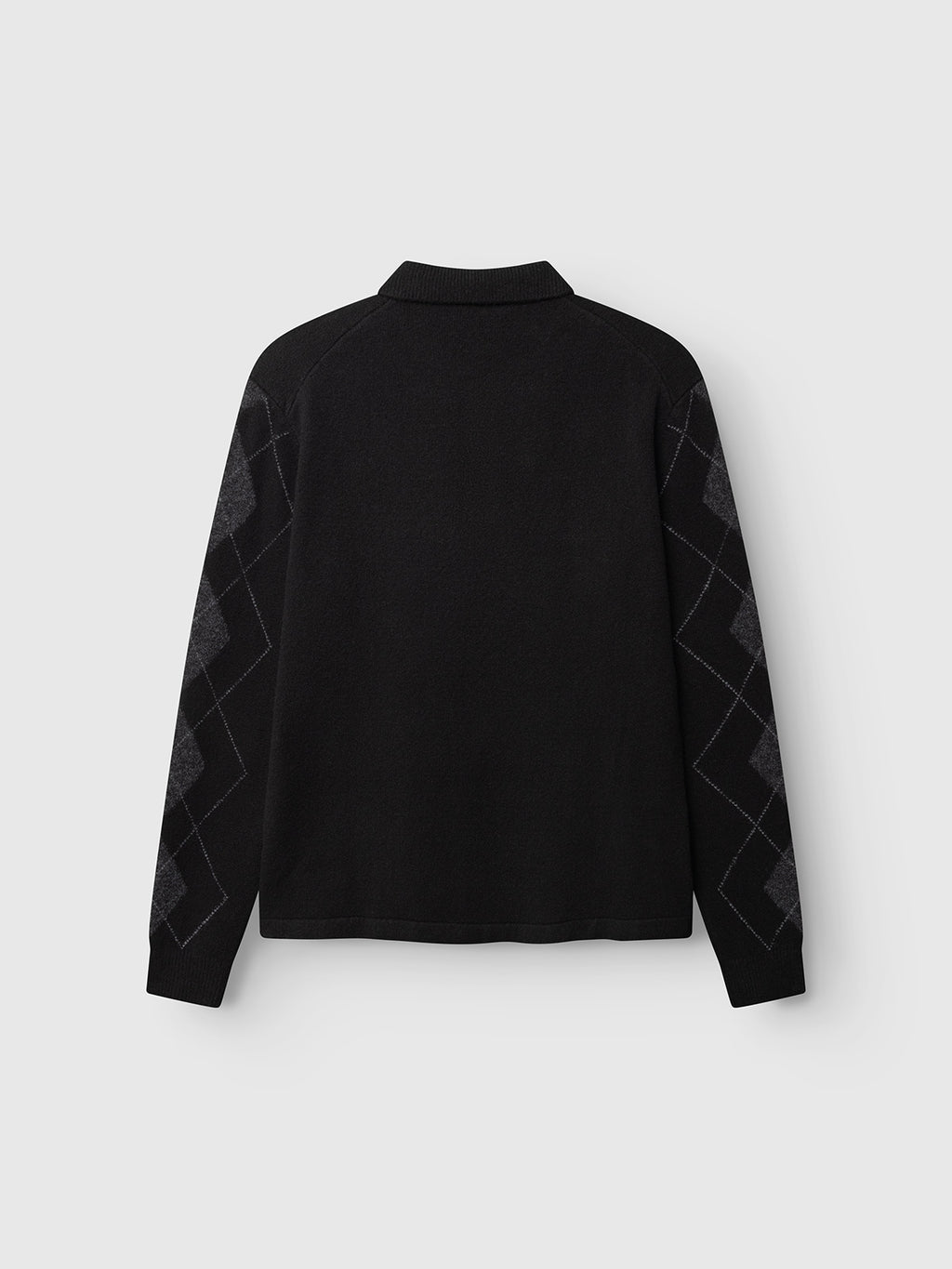 The GABpietro Polo Argyle LS Knit - Black by Gabba is displayed from the back, featuring a long-sleeve polo design with a collar. Dark gray, subtle argyle patterns adorn the sleeves, emphasizing its modern knit style. Crafted from a cotton blend in a boxy relaxed fit, this contemporary piece stands out against a plain light gray background.