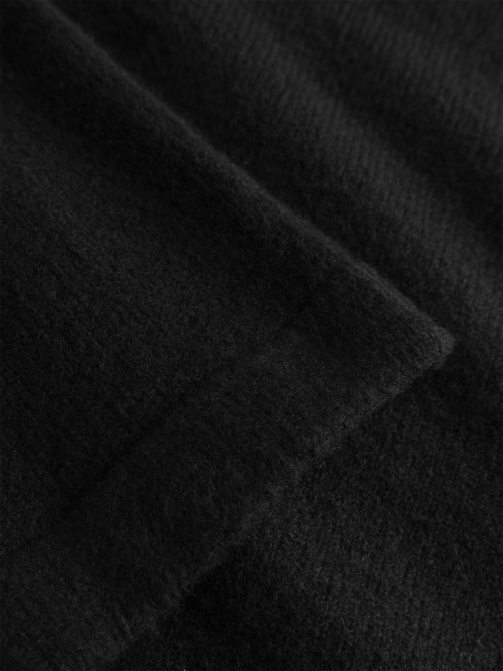 Close-up of the GABpietro Polo Argyle LS Knit in black by Gabba, showcasing its soft knit fabric with a visible seam and slightly fuzzy texture, featuring subtle argyle detailing for an elegant touch.