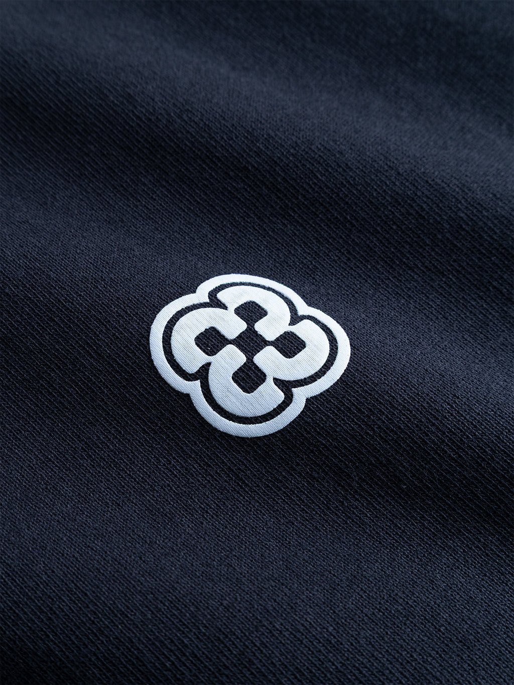 A white geometric logo resembling an interlocking knot is printed on the dark, textured cotton jersey of the Gabba GABlegin Wix Boxy Hour Lobby2 SS T-shirt in Night Sky.