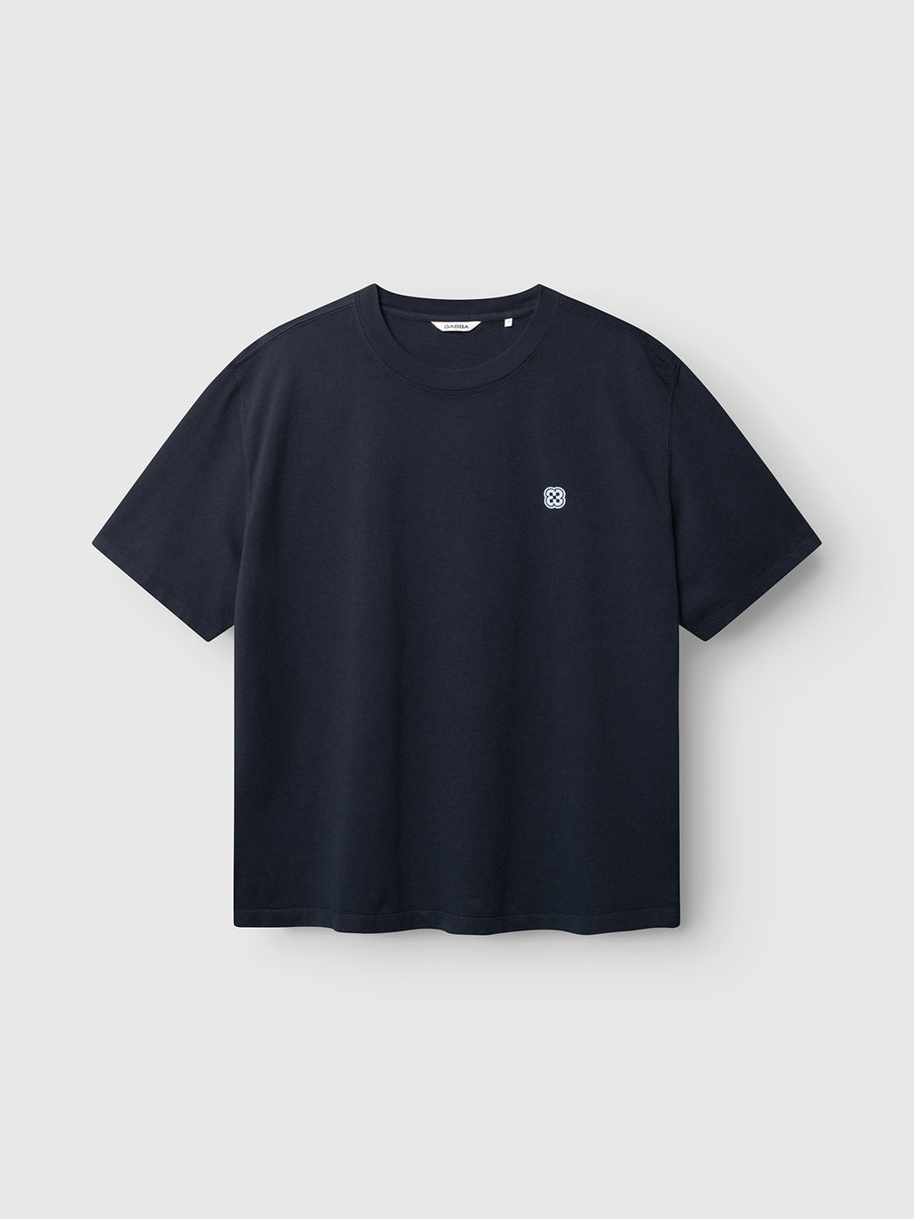 The Gabba GABlegin Wix Boxy Hour Lobby2 SS T-shirt in Night Sky features a plain black, short-sleeve design with a small circular white logo on the left chest. Crafted from textured cotton jersey for enhanced comfort, the t-shirt is shown against a light gray background.