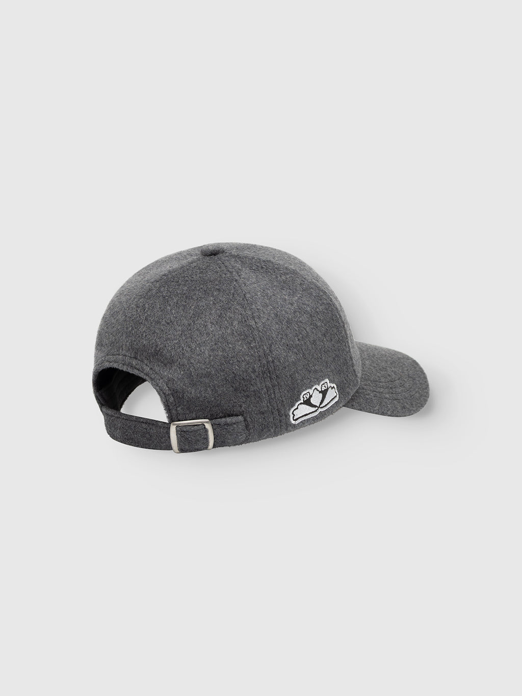 The Gabba GABlimo W Lobby Cap in Grey Mel is a six-panel wool-blend cap, shown from the back with an adjustable strap and metal buckle. It features a small mountain patch above the opening on the left side and displays subtle embroidered artwork for extra detail, combining comfort and durability.