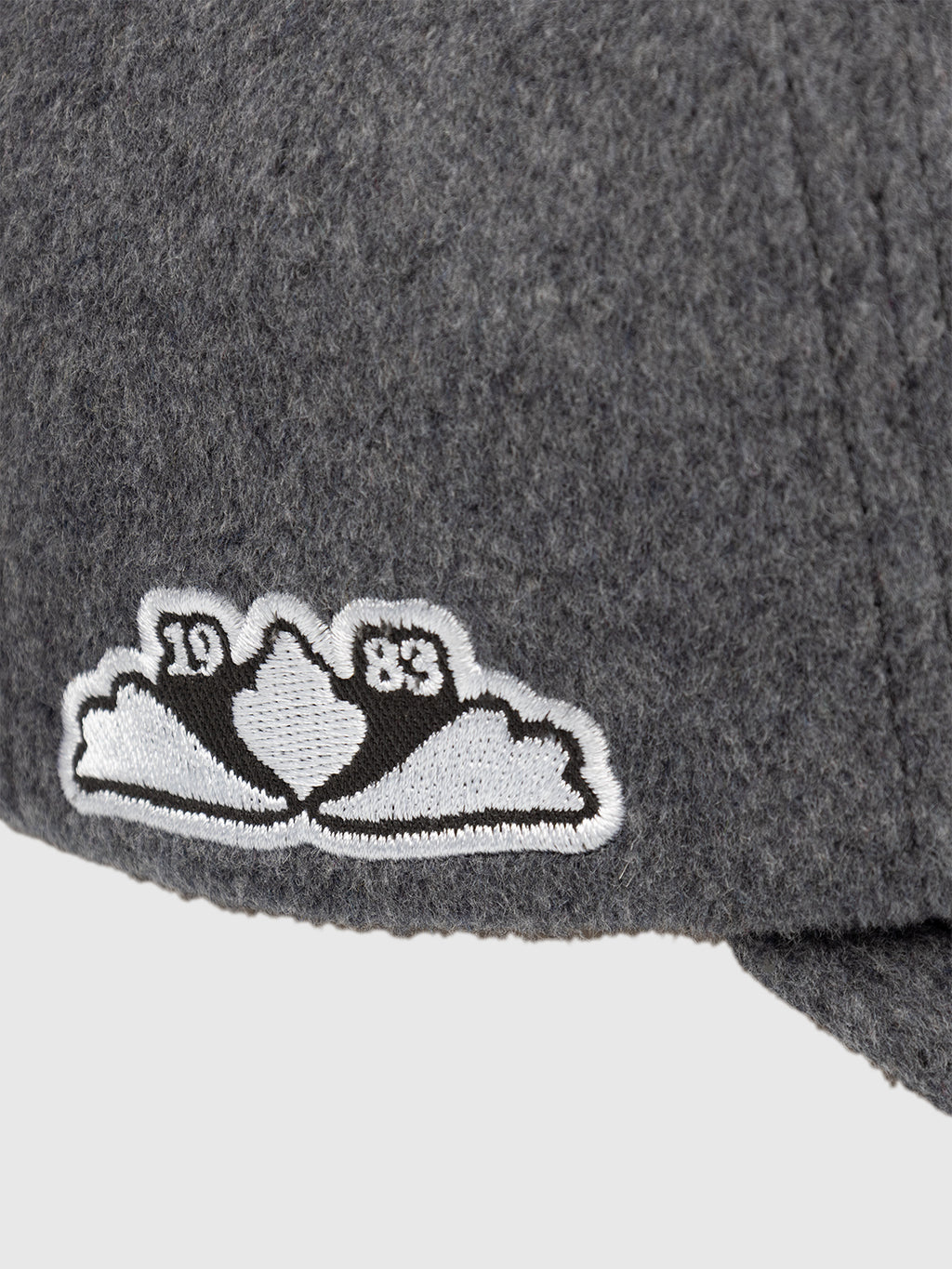 Close-up of the Gabba GABlimo W Lobby Cap in Grey Mel, a gray wool-blend six-panel cap featuring a white and black embroidered patch with cloud shapes and the numbers 19 and 83 on each side of the design.