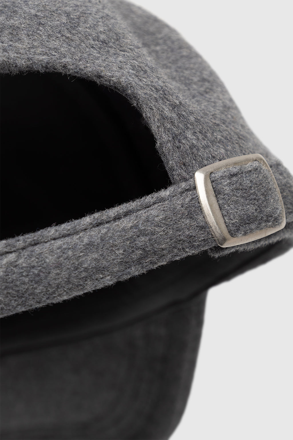 Close-up of the back of the Gabba GABlimo W Lobby Cap in Grey Mel, a six-panel cap crafted from a wool-blend, featuring an adjustable strap with a silver metal buckle against a light gray background.