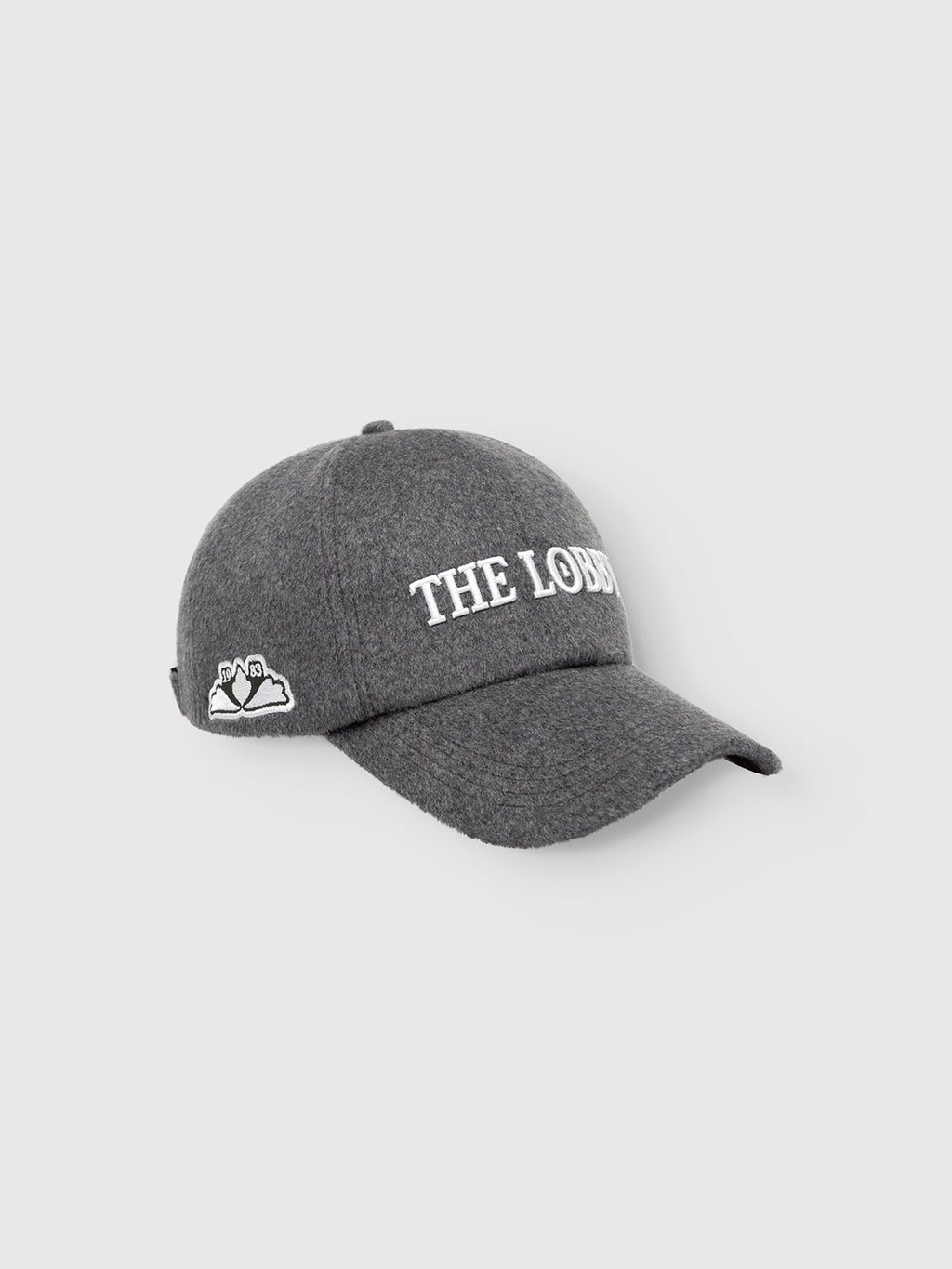 The Gabba GABlimo W Lobby Cap - Grey Mel is a gray wool-blend six-panel cap featuring “THE LOBBY” embroidered in white on the front and a small white cloud and sun motif on the side, showcased against a light background. This classic accessory blends understated design with everyday style.