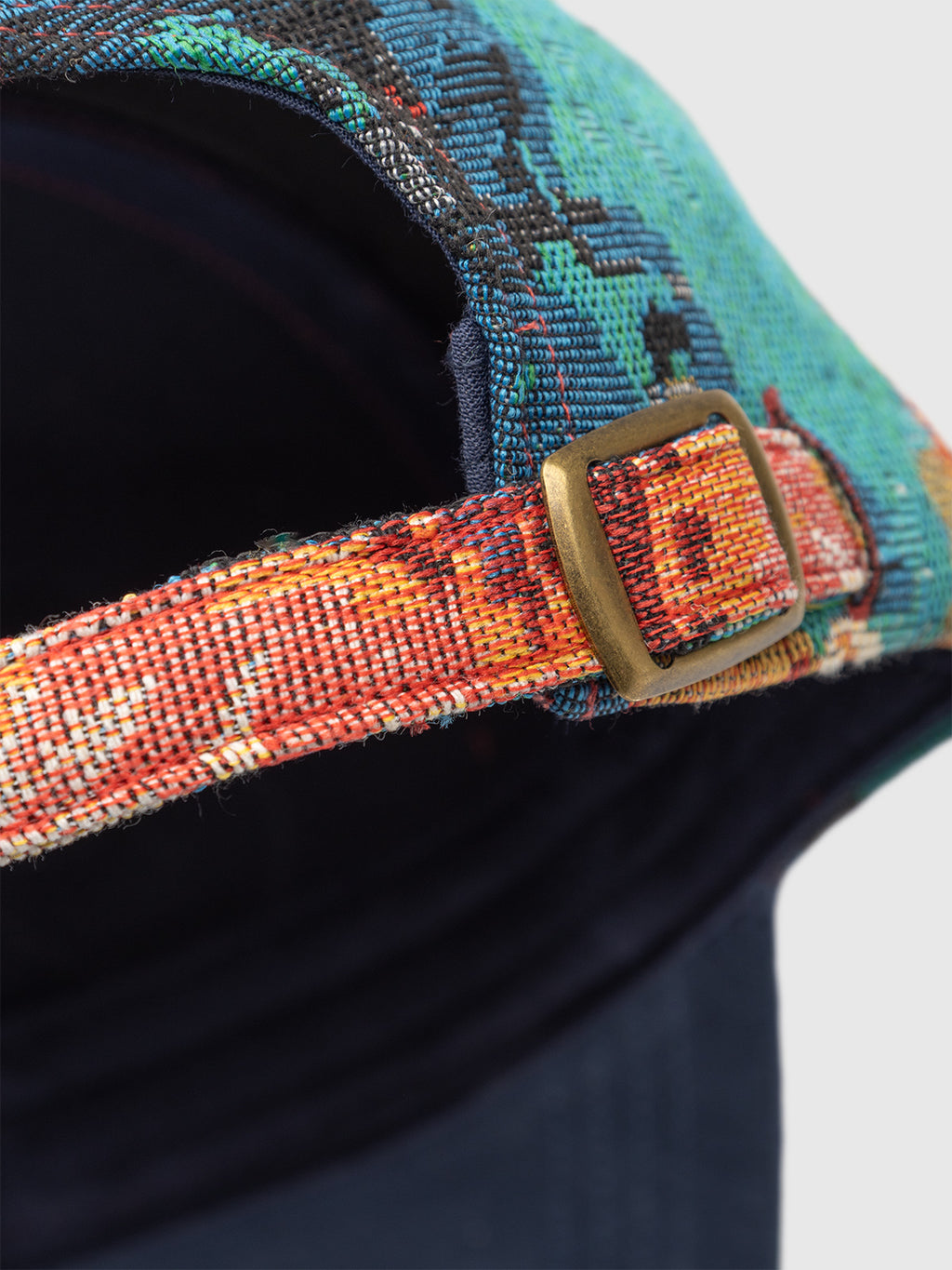 Close-up of the back of the Gabba GABrichi Fiore Cap - Multi Pattern, showcasing its multicolored jacquard design, adjustable strap with a small brass buckle, and embroidered Gabba logo, set against a plain light gray background.