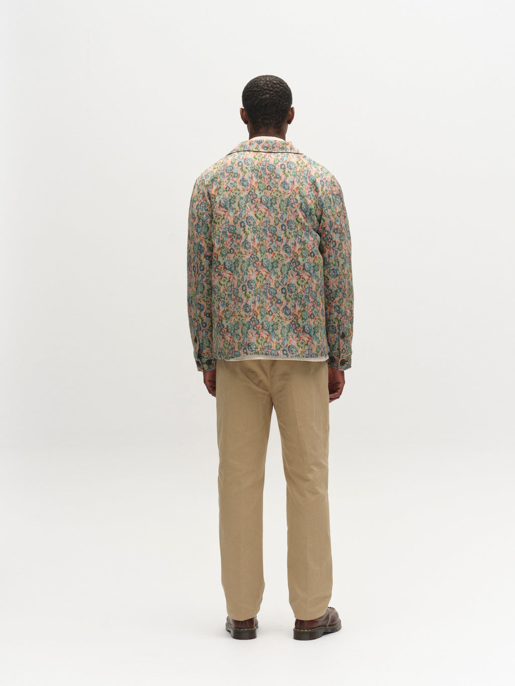 A person faces away from the camera, wearing a Gabba GABaustin POKT Kscope LS Overshirt - Abstract Flowers, styled as a textured overshirt with beige pants and brown shoes against a plain white background.