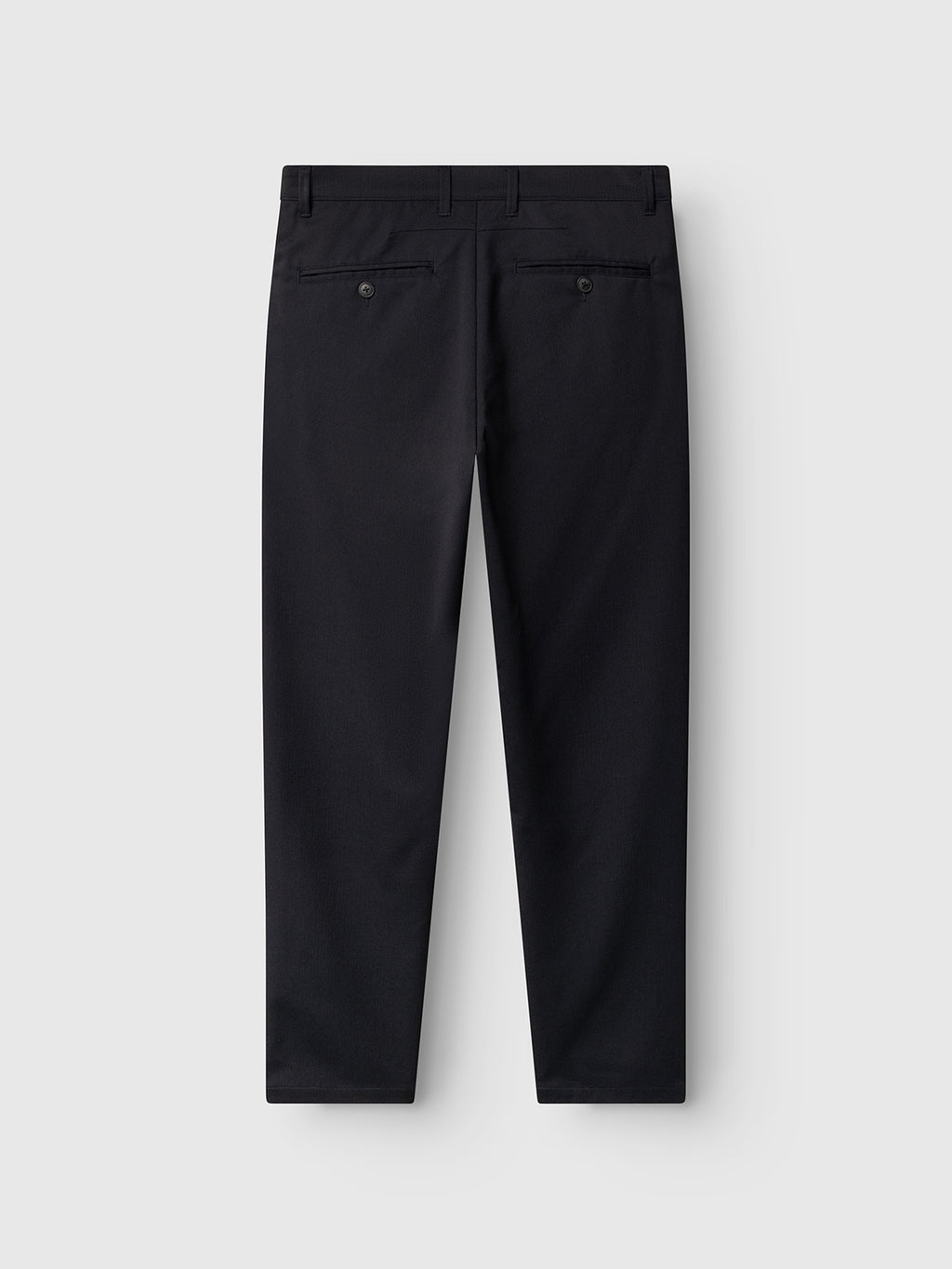 Back view of the Gabba GABpaul Deme Pant in Dark Navy, featuring belt loops, two buttoned back pockets, and straight legs. Crafted from a refined micro-pattern woven fabric, these dress pants are displayed on a light gray background—perfect for everyday wear.
