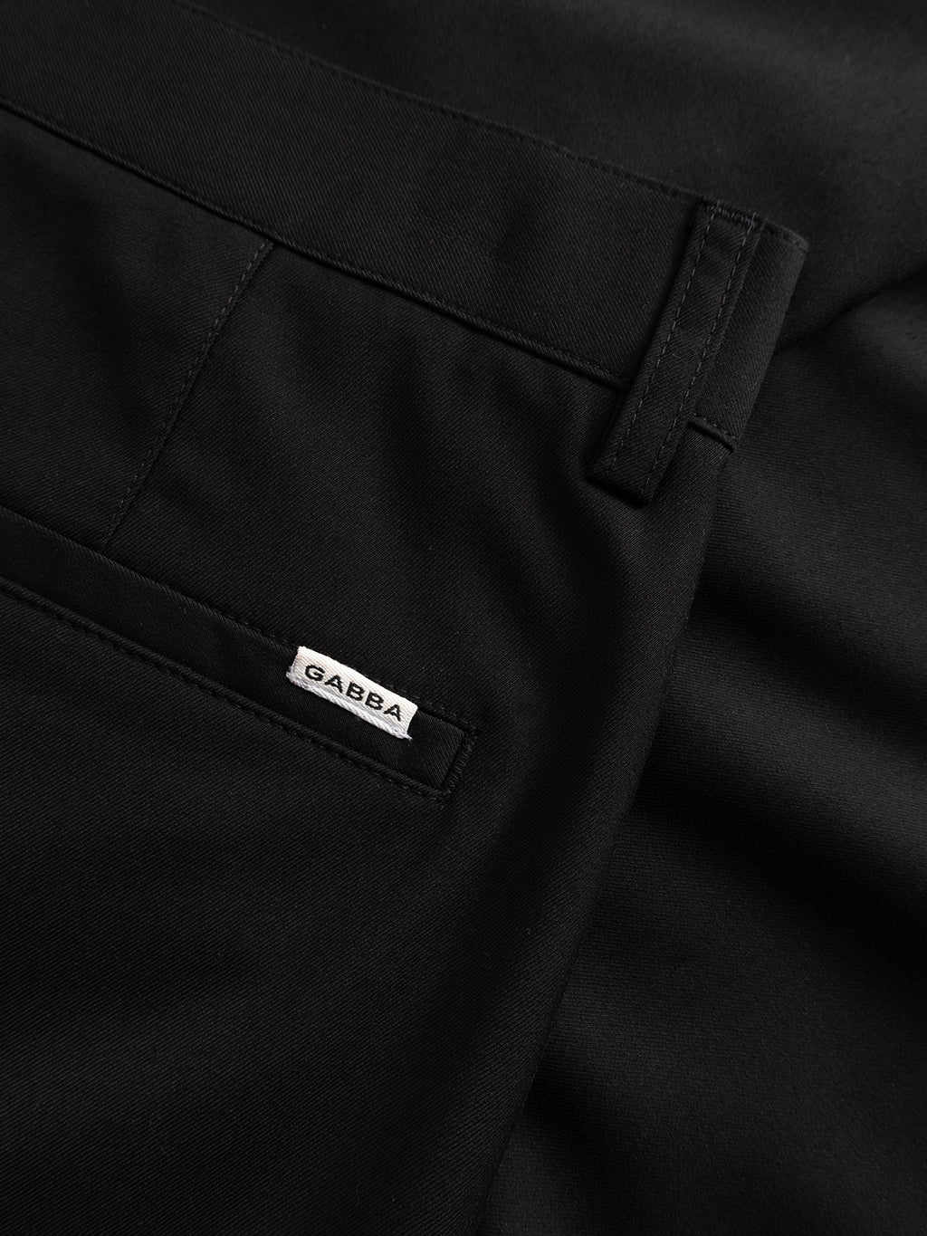 Close-up of the pocket area of black GABjoe Turnup Fin Pant by Gabba, featuring a small white tag with the brand name sewn above the pocket.