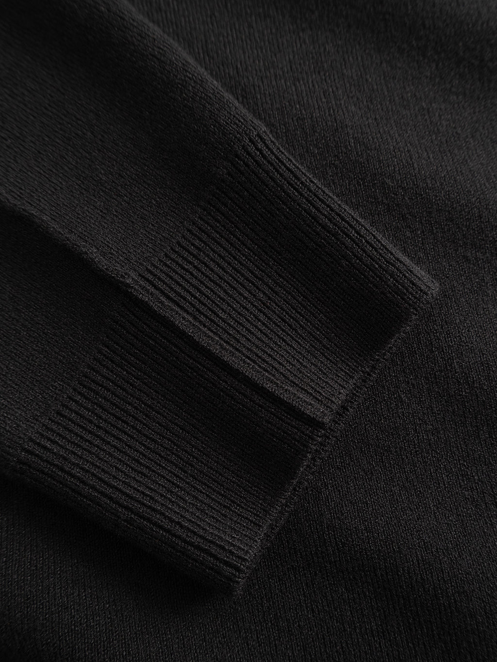 Close-up of the sleeve of the Gabba GABadriel Half Zip Lume LS Knit in Meteorite, laid flat to showcase the black ribbed viscose blend fabric’s texture and knit pattern.
