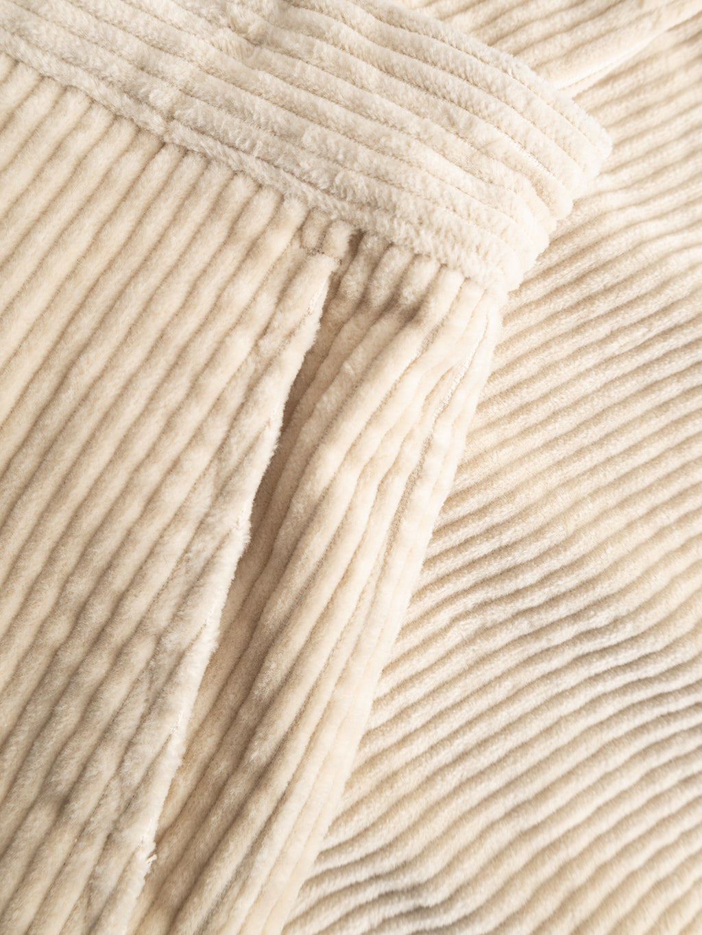 Close-up of the GABjoe Nopleats Ibre Pant in Birch by Gabba featuring a soft, cream-colored stretch corduroy fabric with visible ribbed texture and gentle folds, evoking the comfort and style reminiscent of classic chino construction.