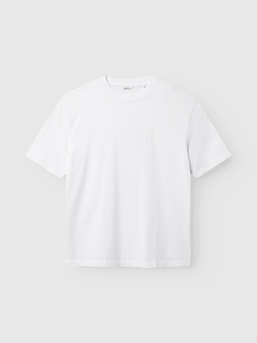 The GABlegin Wix Boxy Hour SS T-shirt in white by Gabba is displayed against a light gray background. Crafted from soft cotton jersey, this short-sleeve shirt features a classic crew neckline and a relaxed boxy fit, with no visible designs except for an understated embroidered Gabba logo.