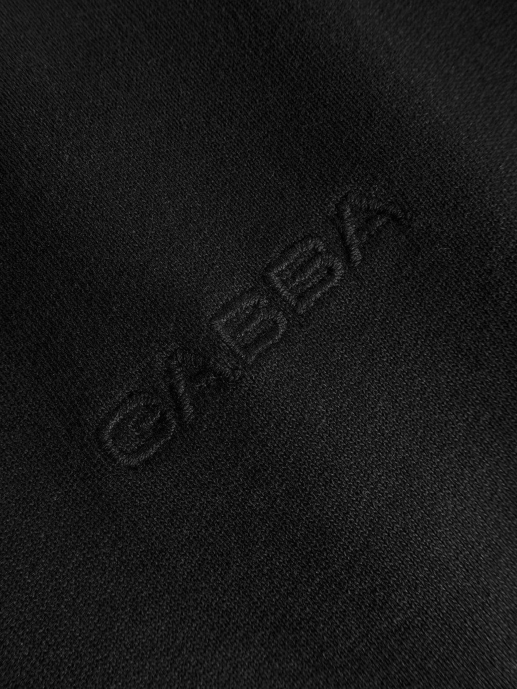 Close-up of the Gabba GABlegin Wix Boxy Hour SS T-shirt in black, featuring mid-weight cotton jersey fabric with “GABBA” subtly embroidered in matching black thread—a textured, understated branding detail that perfectly complements its relaxed boxy fit.