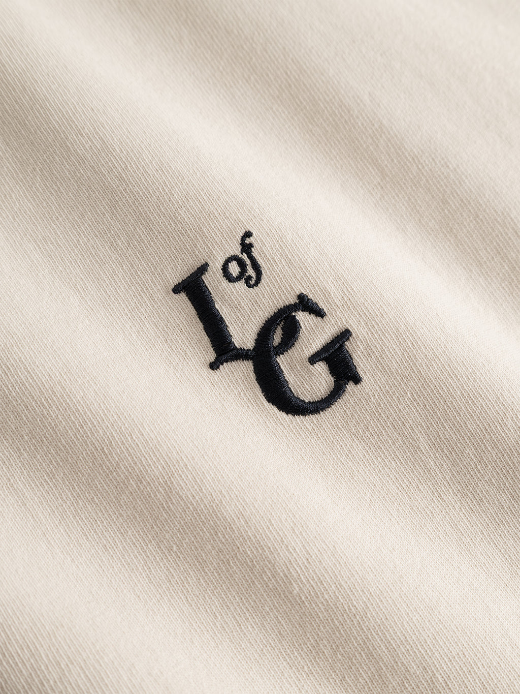 Close-up of the Gabba GABlegin Boxy Glory SS T-Shirt in Birch, showcasing its soft, slightly textured beige cotton jersey fabric with black “L of G” embroidered text.