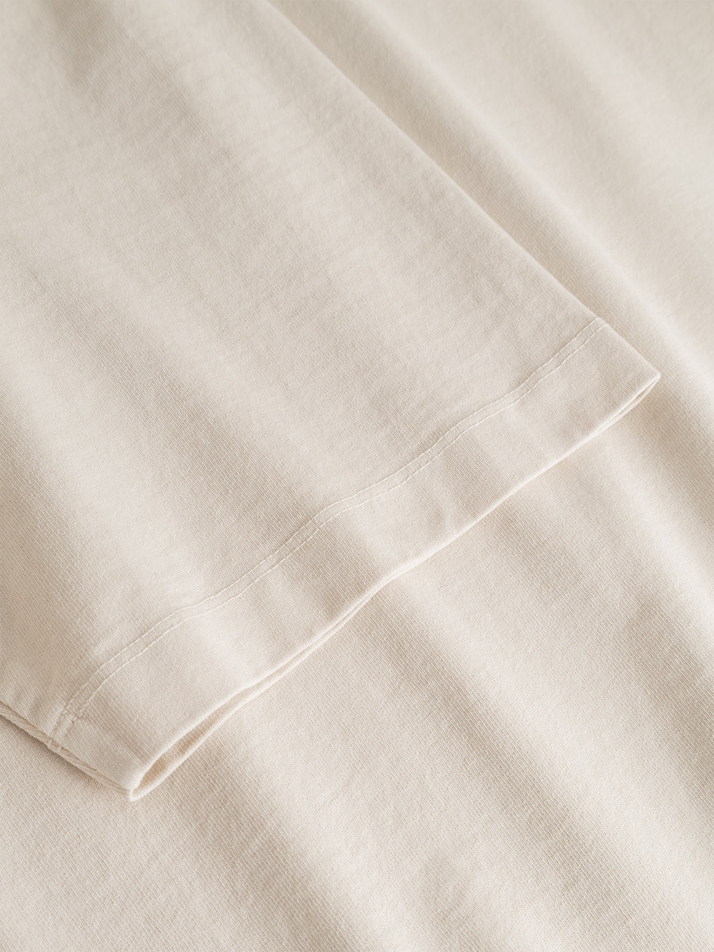 Close-up of the hem and fabric of the Gabba GABlegin Boxy Glory SS T-Shirt in Birch, laid flat to showcase stitching details and the soft, smooth texture of the textured cotton jersey. The relaxed boxy fit is emphasized by the carefully constructed seams and subtle drape of the material.