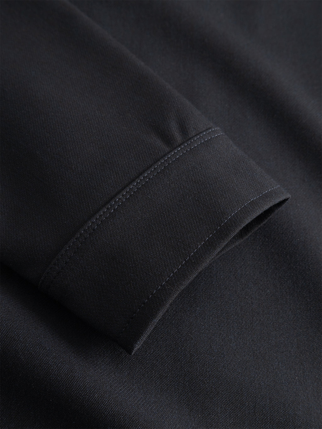 Close-up of the Gabba GABtogger Push Phin LS Overshirt GRS in Blue Black, showcasing the cuff with visible stitching detail. Crafted from a luxurious wool-viscose blend, the fabric appears smooth with a subtle sheen. This regular fit overshirt is a versatile layering essential for any wardrobe.