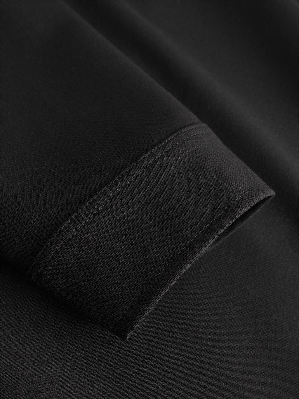 Close-up of the GABtogger Push Phin LS Overshirt GRS in black by Gabba, crafted from a black wool-viscose blend. The image details a precisely stitched seam—likely at the cuff—highlighting the overshirt’s fine texture and clean, straight stitching lines. A regular-fit essential, it’s perfect for layering.