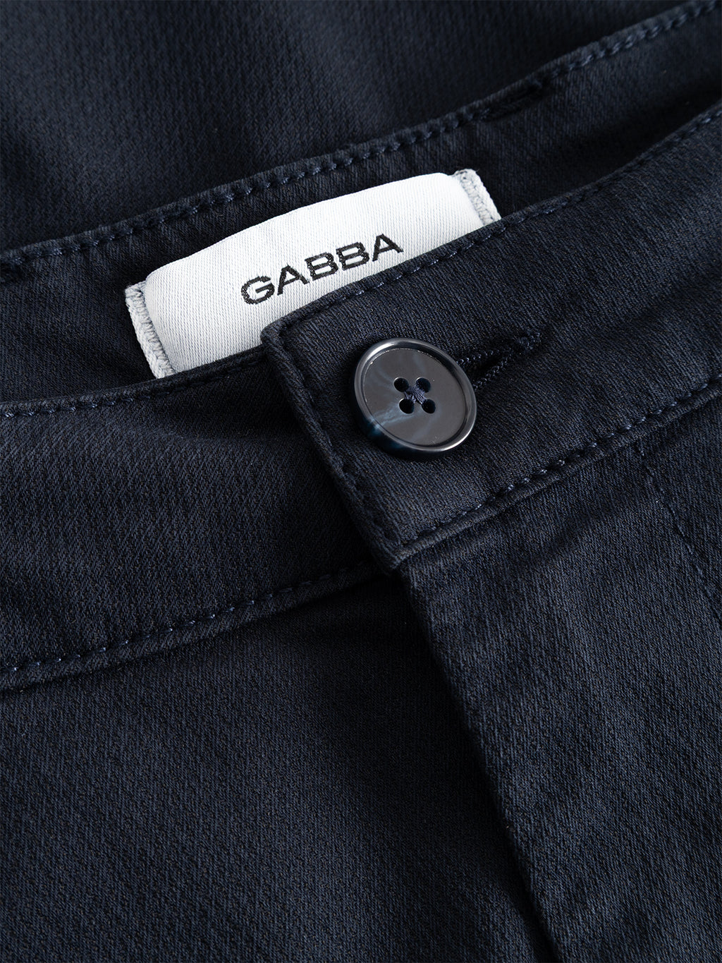Close-up of the GABjoe-pas Dale Pant - Blue Black by Gabba, featuring a navy blue tapered fit with a black button and a white “GABBA” label sewn into the waistband, crafted from high-stretch cotton-blend fabric for a comfortable and contemporary silhouette.