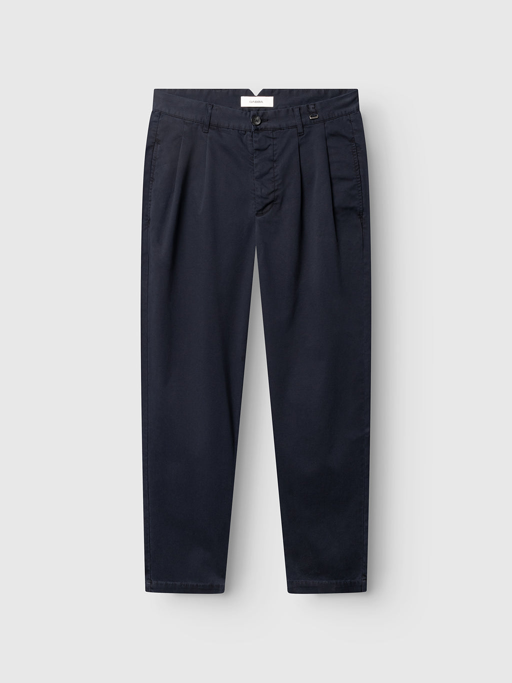 The GABfirenze Cropped Marlo Pant by Gabba in Dark Navy is showcased laid flat on a light gray background. Crafted from garment-dyed dobby fabric, these relaxed fit trousers feature pleats, a button and zipper closure, belt loops, and visible side pockets—offering both comfort and style for any occasion.