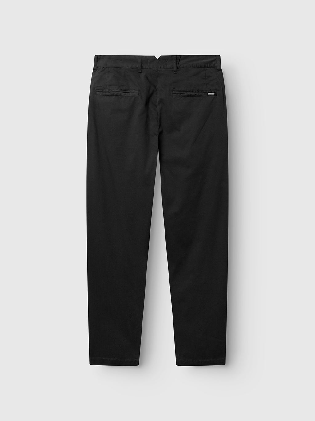 The GABfirenze Cropped Marlo Pant in black by Gabba is displayed from the back, crafted from garment-dyed dobby fabric for a refined texture. These relaxed-fit pants feature two welt pockets, a small label on the right pocket, and are showcased against a plain light gray background.