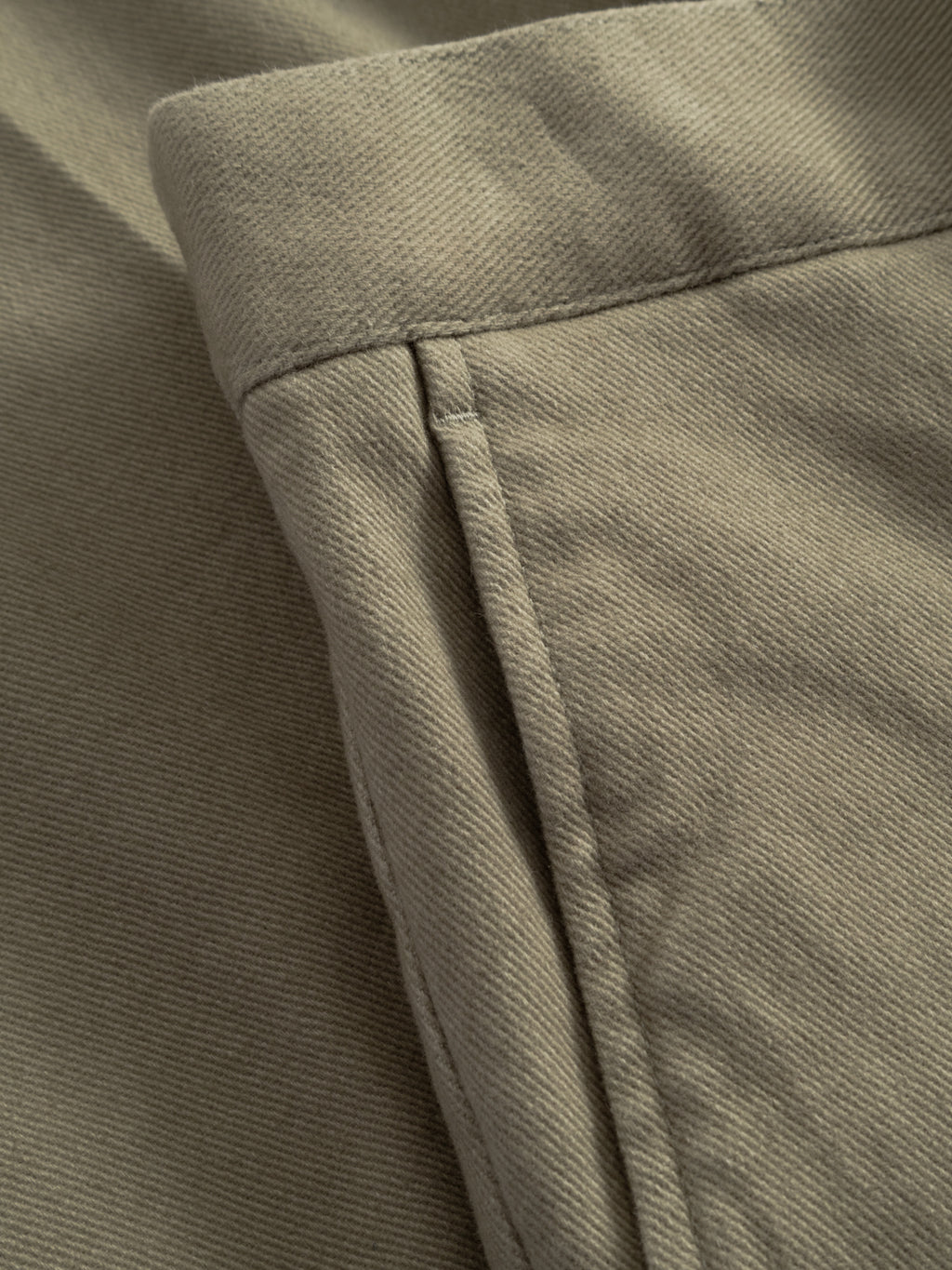 Close-up of stretch twill fabric in green on Gabba's GABdenver Elastic Twill Pant, highlighting the seam, stitching, texture, and elasticated waist detail of these loose-fit pants.