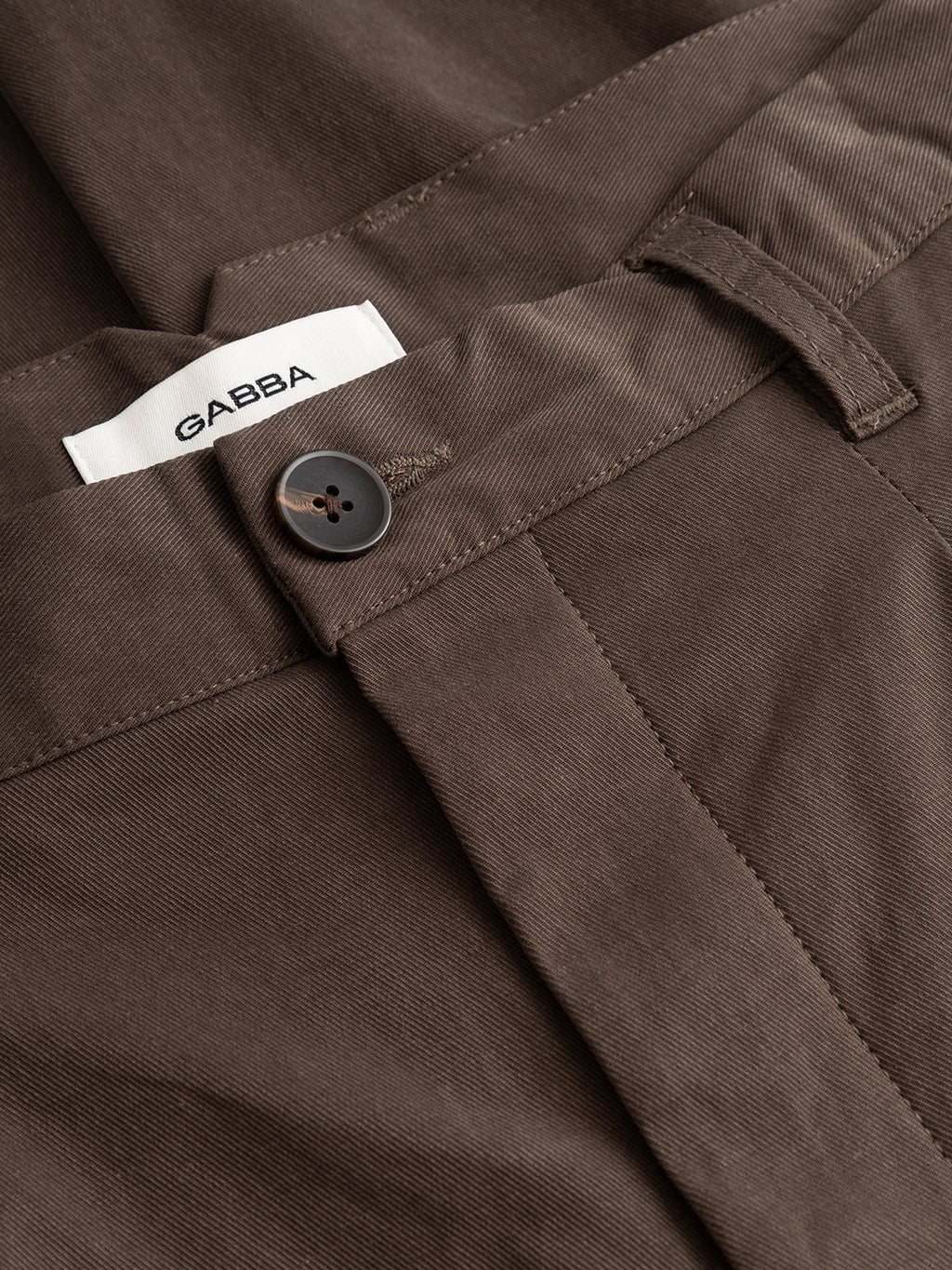 Close-up of relaxed fit brown GABfirenze Bolu Cropped TENCEL ™ Pant - Brown Slate trousers with a button fly and a white interior brand label.