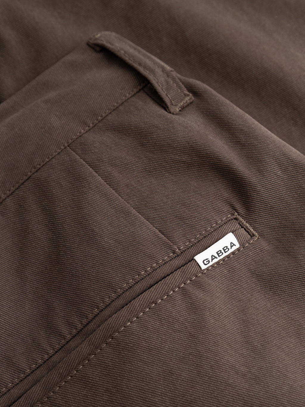 Close-up of relaxed fit brown GABfirenze Bolu Cropped TENCEL ™ Pant - Brown Slate trousers showing a belt loop and a small white brand tag sewn into the pocket seam.