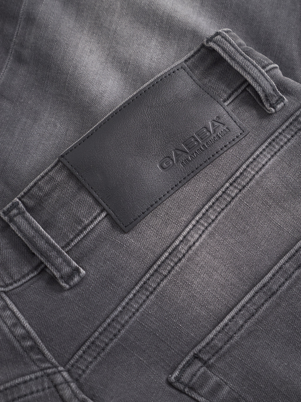 Close-up of the back pocket and waistband of GABBA’s GABalex Thor Cropped Jeans in denim wash, featuring a black leather brand patch, fashion-forward fit, and worker-cut waistbands for added style.