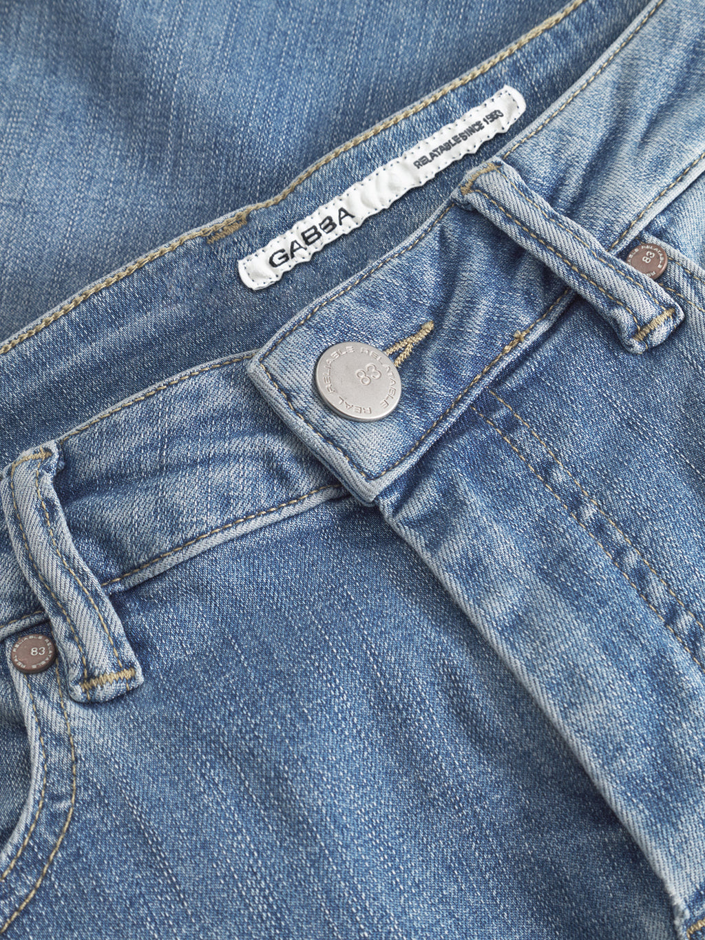 Close-up of GABBA GABjones K2615 Lt. slim fit blue denim jeans, featuring waistband, metal button, belt loops, and inner brand label. Crafted from high-flexibility super-stretch fabric for all-day comfort.