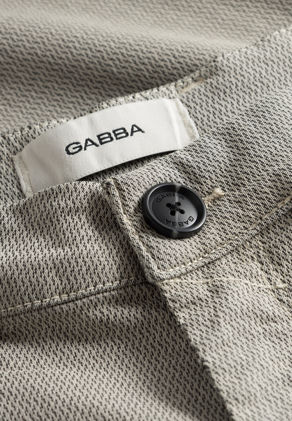 Close-up of GABpaul K3280 Dale Chino in Birch by Gabba, featuring a beige textured slim fit, French pockets, black button, and a white label with the Gabba brand name.